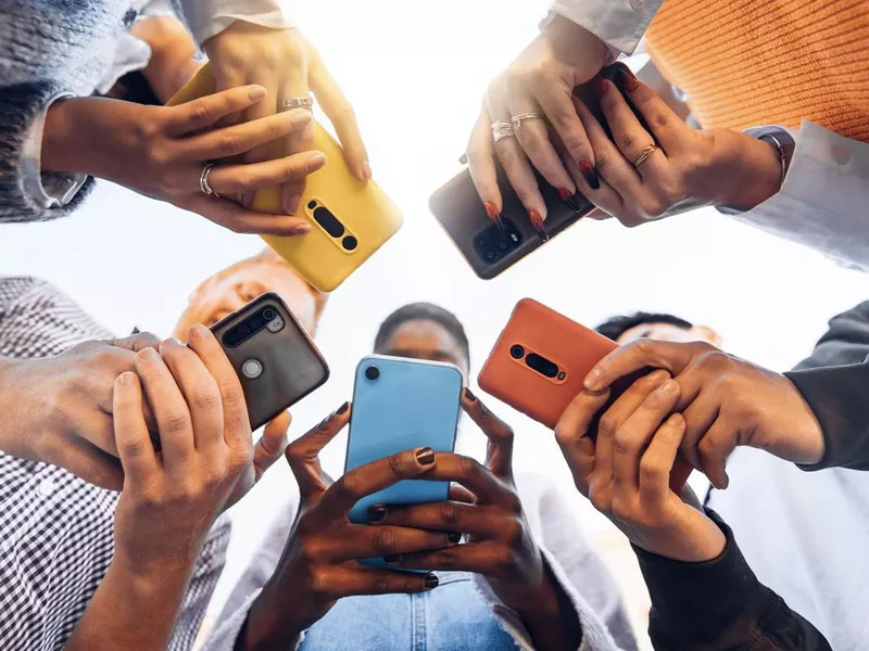 Teens in circle holding smart mobile phones