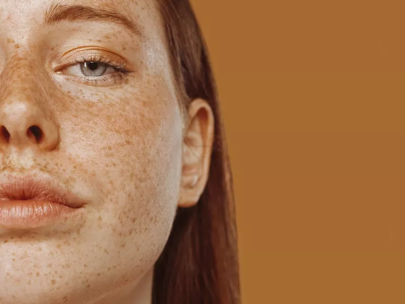 Close-up portrait of half face of a red-haired girl with freckle