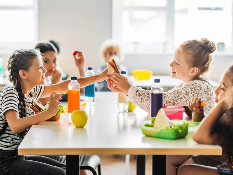 Adorable schoolgirls taking lunch at school cafeteria