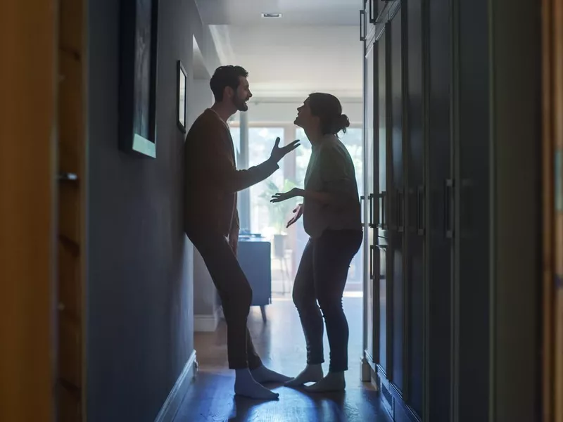 Young Couple Arguing and Fighting. Domestic Violence Scene of Emotional abuse, Stressed Woman and aggressive Man Having Almost Violent Argument in a Dark Claustrophobic Hallway of Apartment.