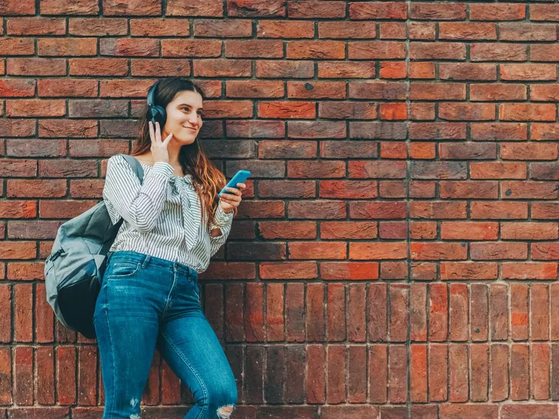 Smiling girl listening music from her phone