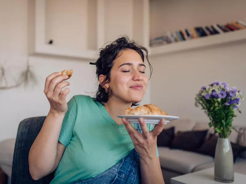 Beautiful girl enjoying the taste of a fresh croissant