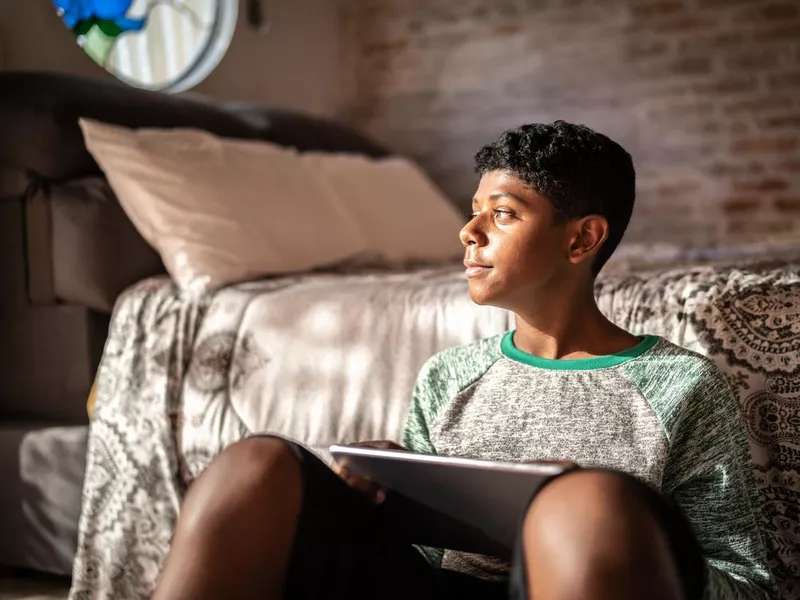 Teenager using digital tablet and looking anxious