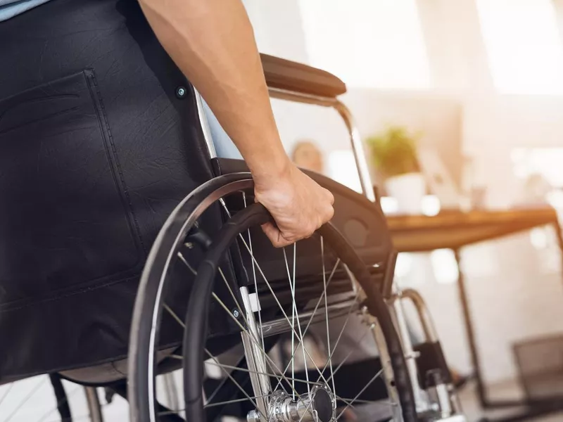 A disabled man is sitting in a wheelchair.