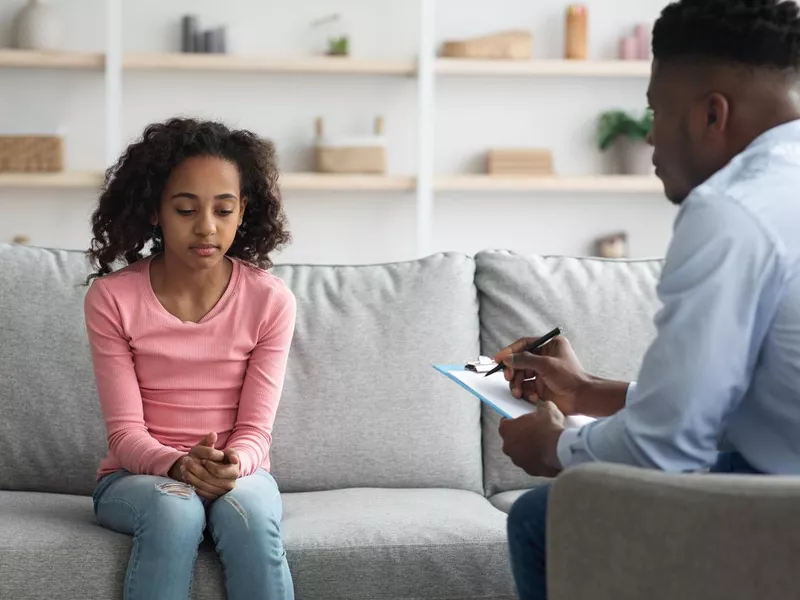 Upset girl having conversation with child psychologist