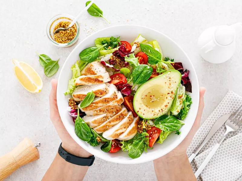 Grilled chicken meat and fresh vegetable salad of tomato, avocado, lettuce and spinach