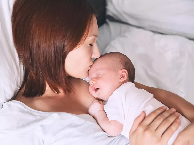 Newborn baby sleeping in the hands of his mother