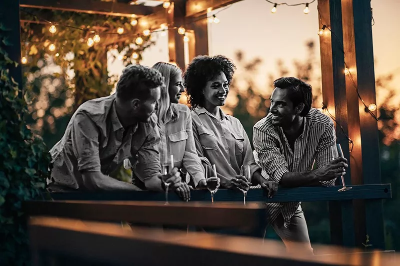 Two cheerful couples socializing at the terrace and enjoying the view