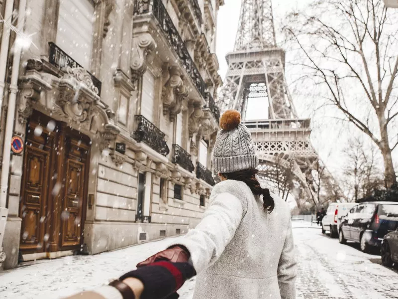 Woman walking to the Eiffel tower with snow