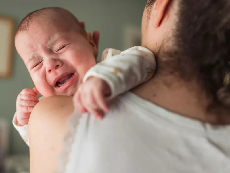 Exhausted baby crying in mother's arms