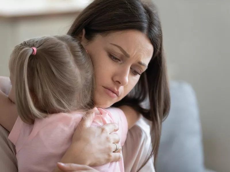 Sad mother embraces little preschool daughter